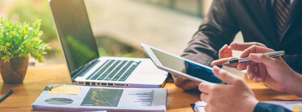 Hands of two individuals holding an ipad while discussing business.